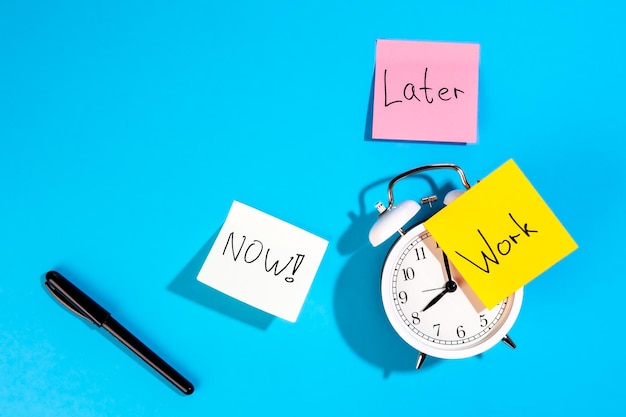 Free photo alarm clock and colorful paper reminders on a blue background top view