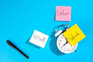 Free photo alarm clock and colorful paper reminders on a blue background top view