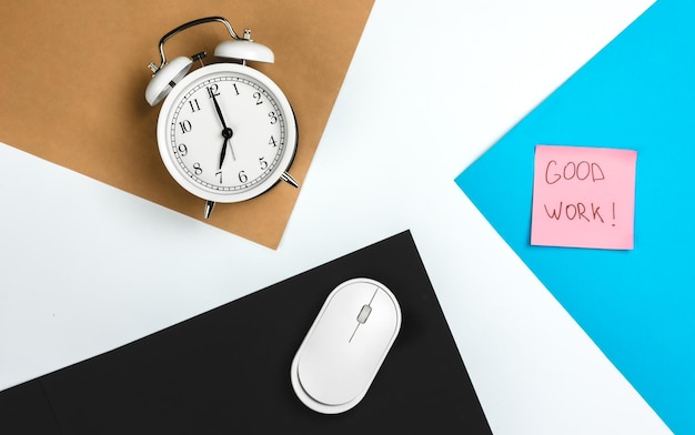 Free photo alarm clock and computer mouse on a colored paper background top view