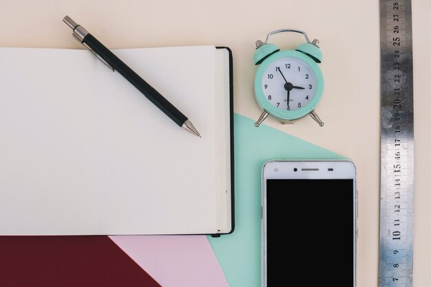 Alarm clock and ruler near smartphone and notebook