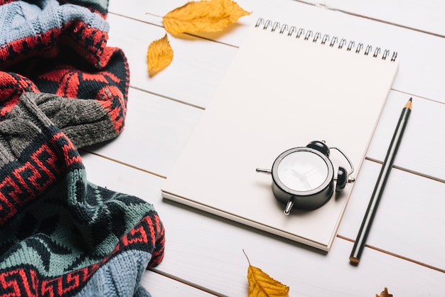 Free Photo alarm clock and stationery near scarf and autumn leaves