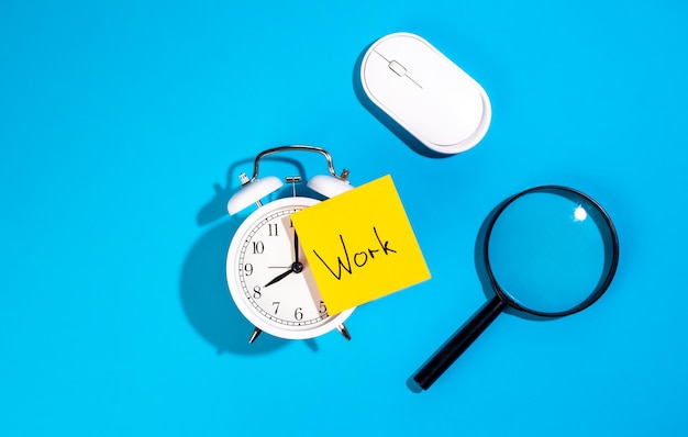 Free Photo alarm clock and a sticker with the inscription work on a blue background