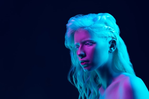 Albino girl with white skin, natural lips and white hair in neon light isolated on black studio background.