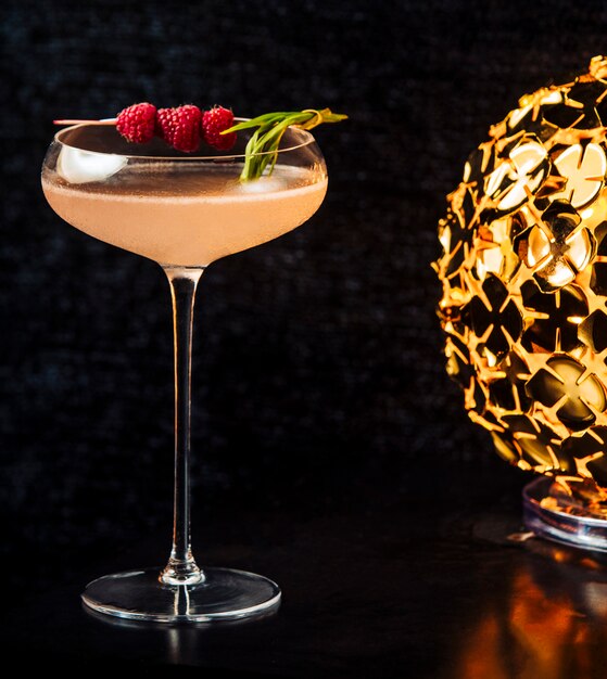 Alcohol drink garnished with rapberries in long stem glass