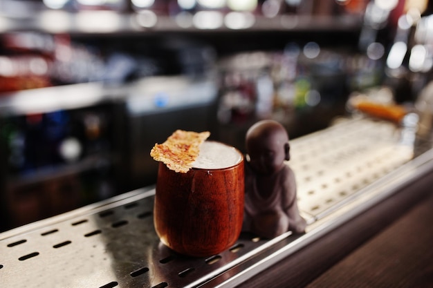 Alcoholic cocktail in wooden cup at bar table