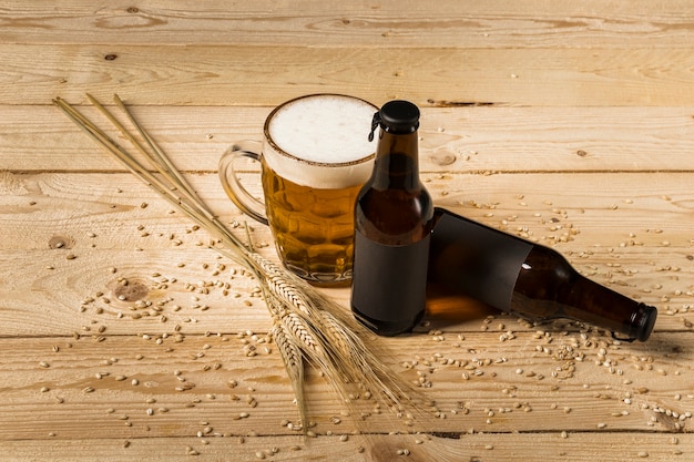 Alcoholic drink and ears of wheat on wooden surface