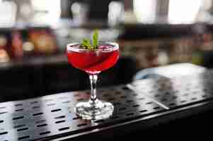 Free photo alcoholic red cocktail with mint on bar table