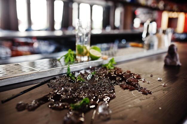 Alcoholic spilled coctail with mint and ice at bar table