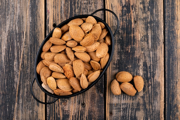 Free photo almond in a black pan on a dark wooden table. top view.