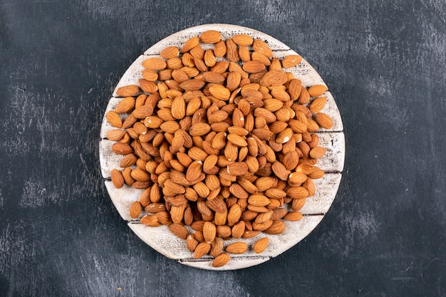 Almond in a wooden board top view on a black stone table