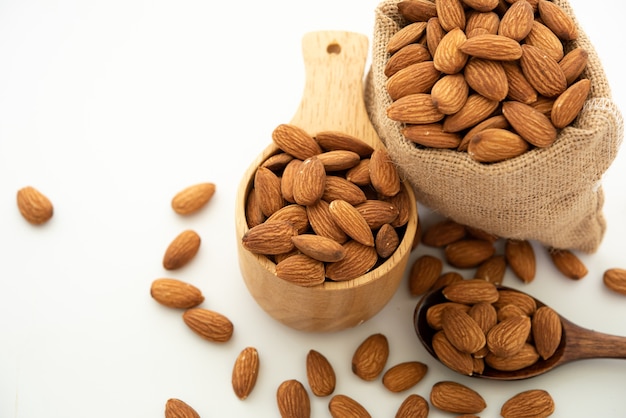 Almond in a wooden spoon and bowl. Sack with almond on white background.