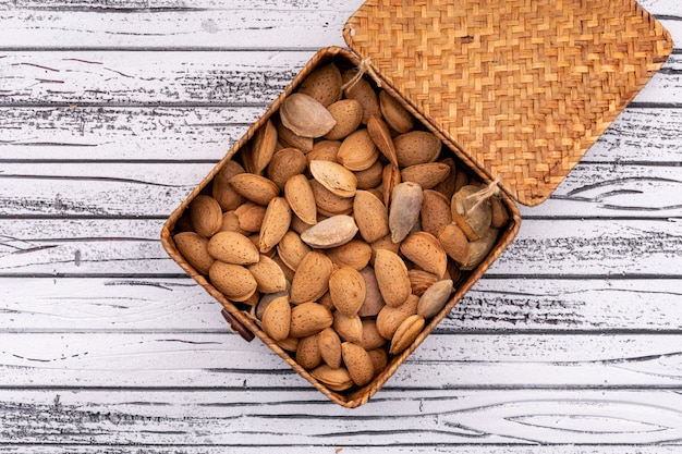 Almonds in box top view on white wooden surface