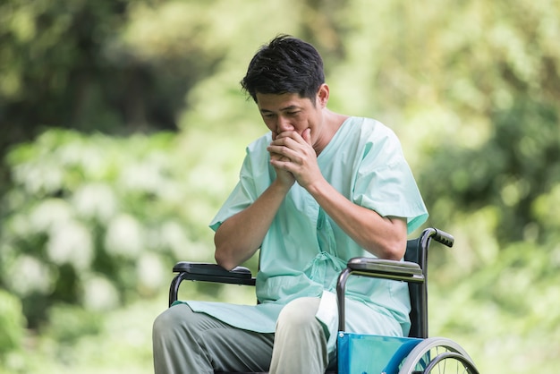 Alone young disabled man in wheelchair at the garden