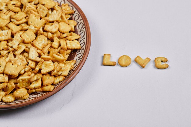 Alphabet crackers on a ceramic plate and word love spelled with crackers.