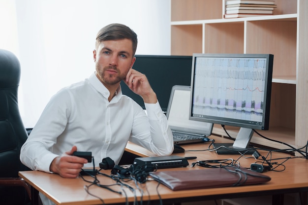 Free photo always glad to help you. polygraph examiner works in the office with his lie detector's equipment