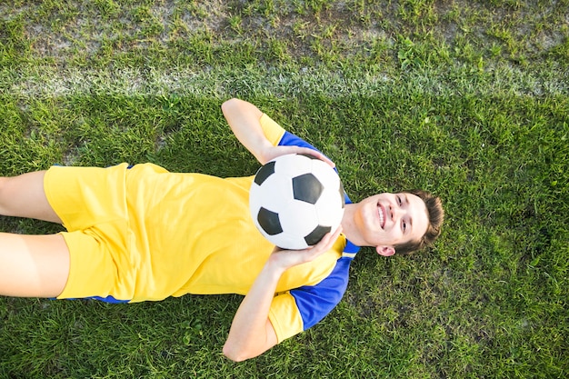 Free photo amateur football concept with lying man throwing ball