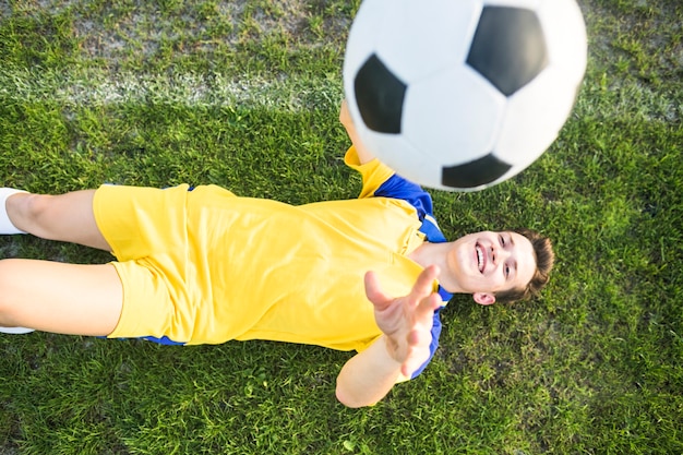 Free photo amateur football concept with lying man throwing ball