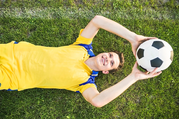 Free photo amateur football concept with lying man throwing ball