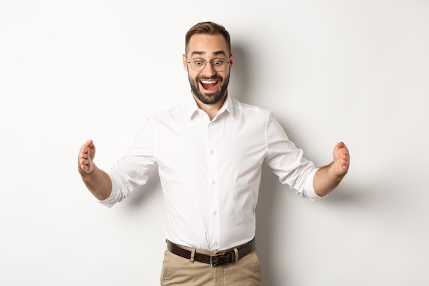 Free photo amazed businessman showing big object, describe something large and looking excited, standing