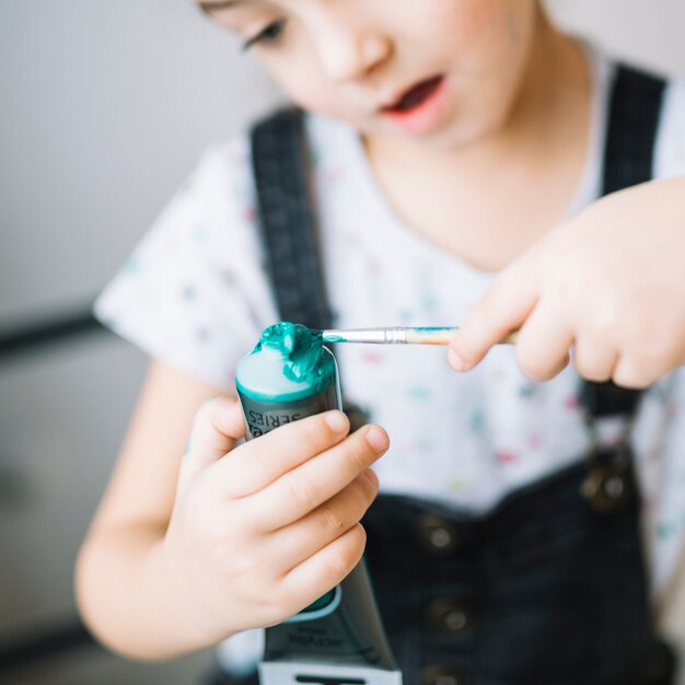 Amazed child with tube of colors and brush in hands