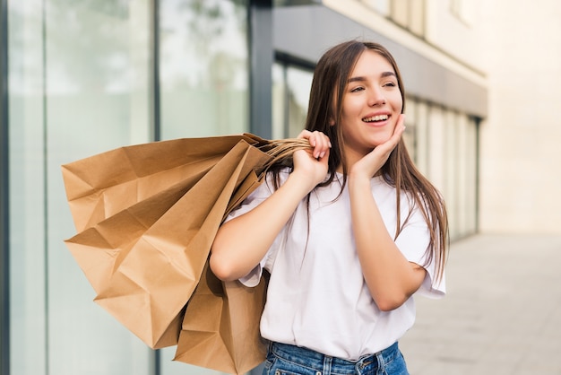 Amazed shopper opening mouth holding shopping bags watching special offers in stores and pointing in the street