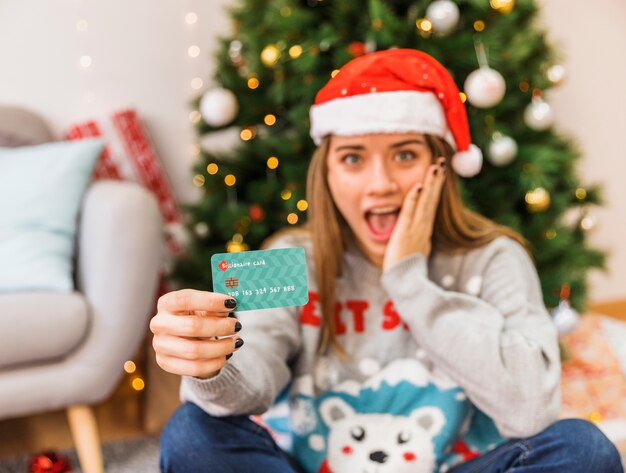 Amazed woman in Christmas hat with credit card 