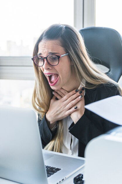 Amazed young businesswoman looking at laptop