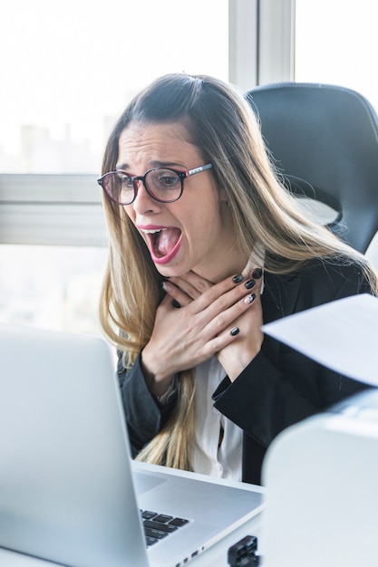 Amazed young businesswoman looking at laptop