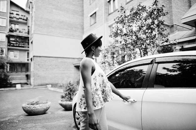 Free photo amazing african american model woman in green pants and black hat posed near white door of car