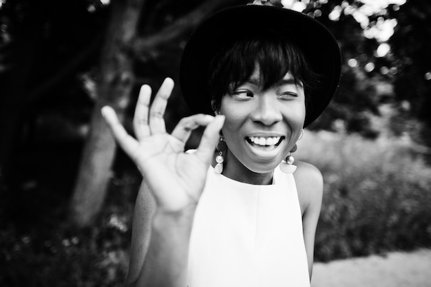 Free photo amazing african american model woman in green pants and black hat posed at park shows ok fingers