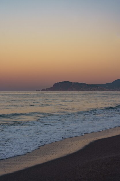 Amazing beach sunset with endless horizon and lonely mountains figures in the distance