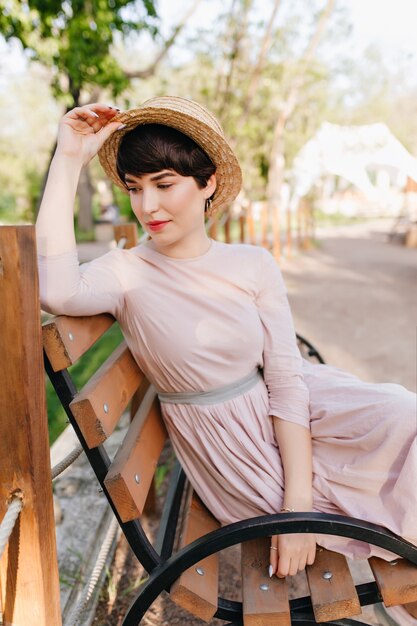 Amazing brunette girl comfortably settled on a wooden bench and thinking about something