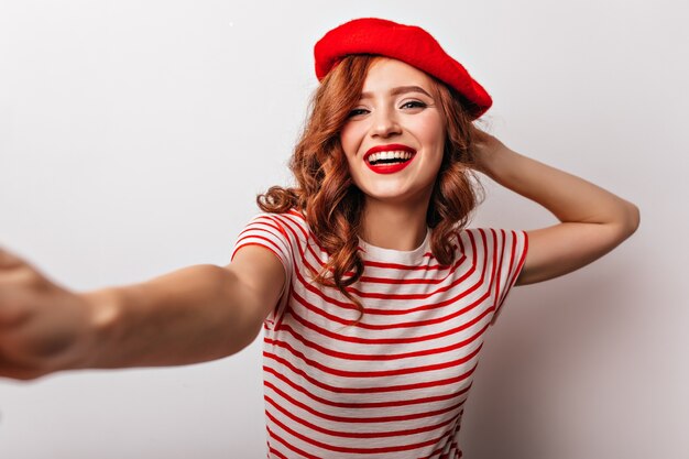 Amazing european girl in red beret laughing  Positive french young woman making selfie.