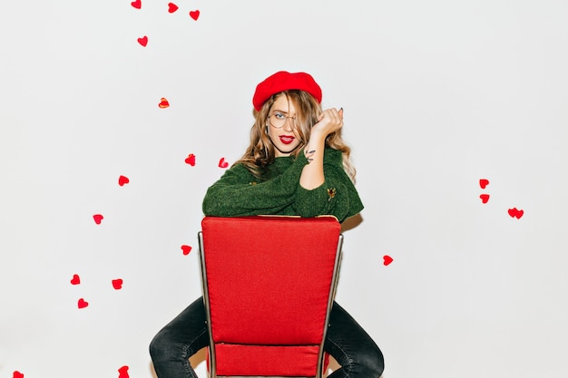 Free photo amazing woman with confident face expression sitting on red chair