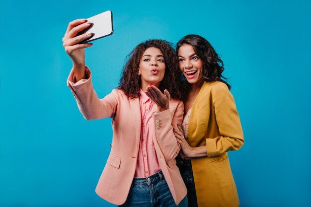 Amazing woman in yellow jacket posing while her friend taking picture