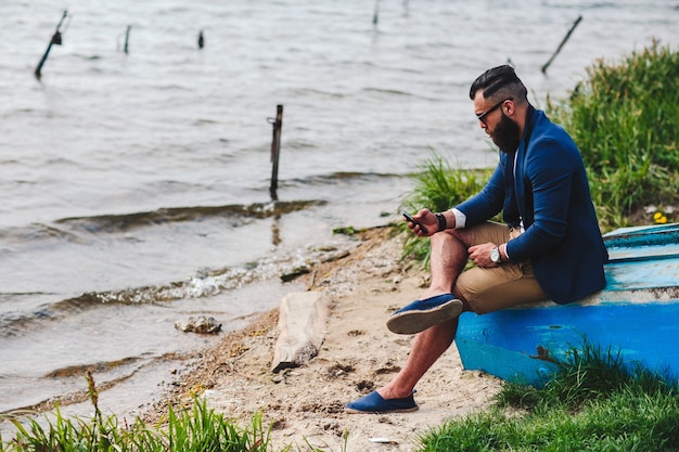 American Bearded Man looks on the river bank in a blue jacket