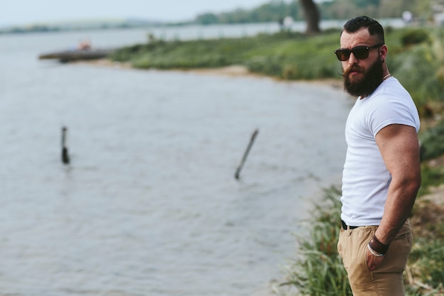 Free Photo american bearded man looks on the river bank in a blue jacket