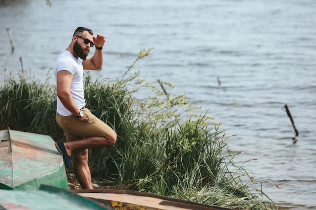 Free photo american bearded man looks on the river bank in a blue jacket