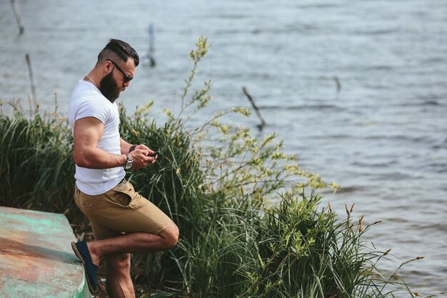 Free photo american bearded man looks on the river bank in a blue jacket