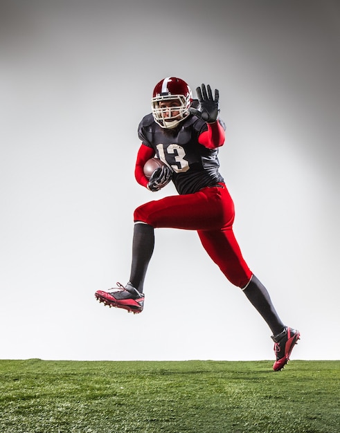 The american football player in action on green grass and gray background.