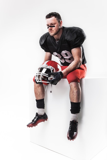 American football player sitting with  helmet