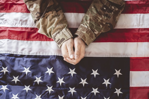 Free photo american soldier mourning and praying with the american flag in front of him