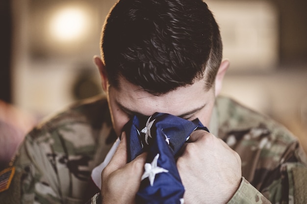 American soldier mourning and praying with the American flag in his hands