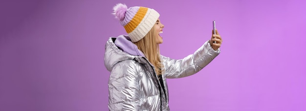 Free Photo amused carefree attractive caucasian blond girl in silver winter jacket hat extend arm holding