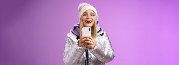 Free Photo amused excited attractive blond girlfriend holding smartphone up recording video boyfriend step snow