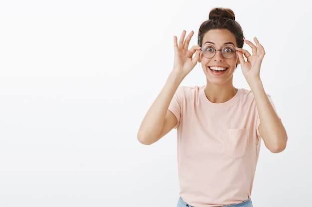 Amused and surprised girl with glasses posing against the white wall