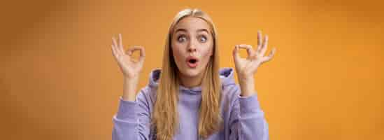 Free photo amused talented creative young blond female tell excellent idea show okay no problem gesture persuade friends everything alright standing excited orange background ok signs folding lips amazed