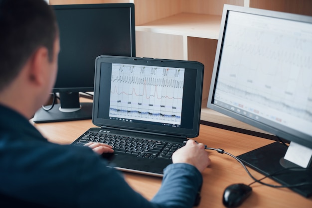 Free Photo analizying information. polygraph examiner works in the office with his lie detector's equipment