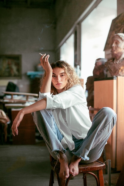 Free Photo analog portrait of beautiful woman posing indoors while smoking a cigarette