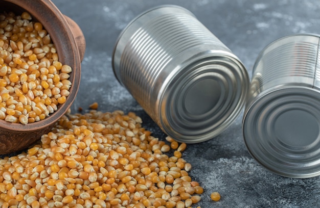 An ancient bowl full of uncooked popcorn seeds with metallic cans.